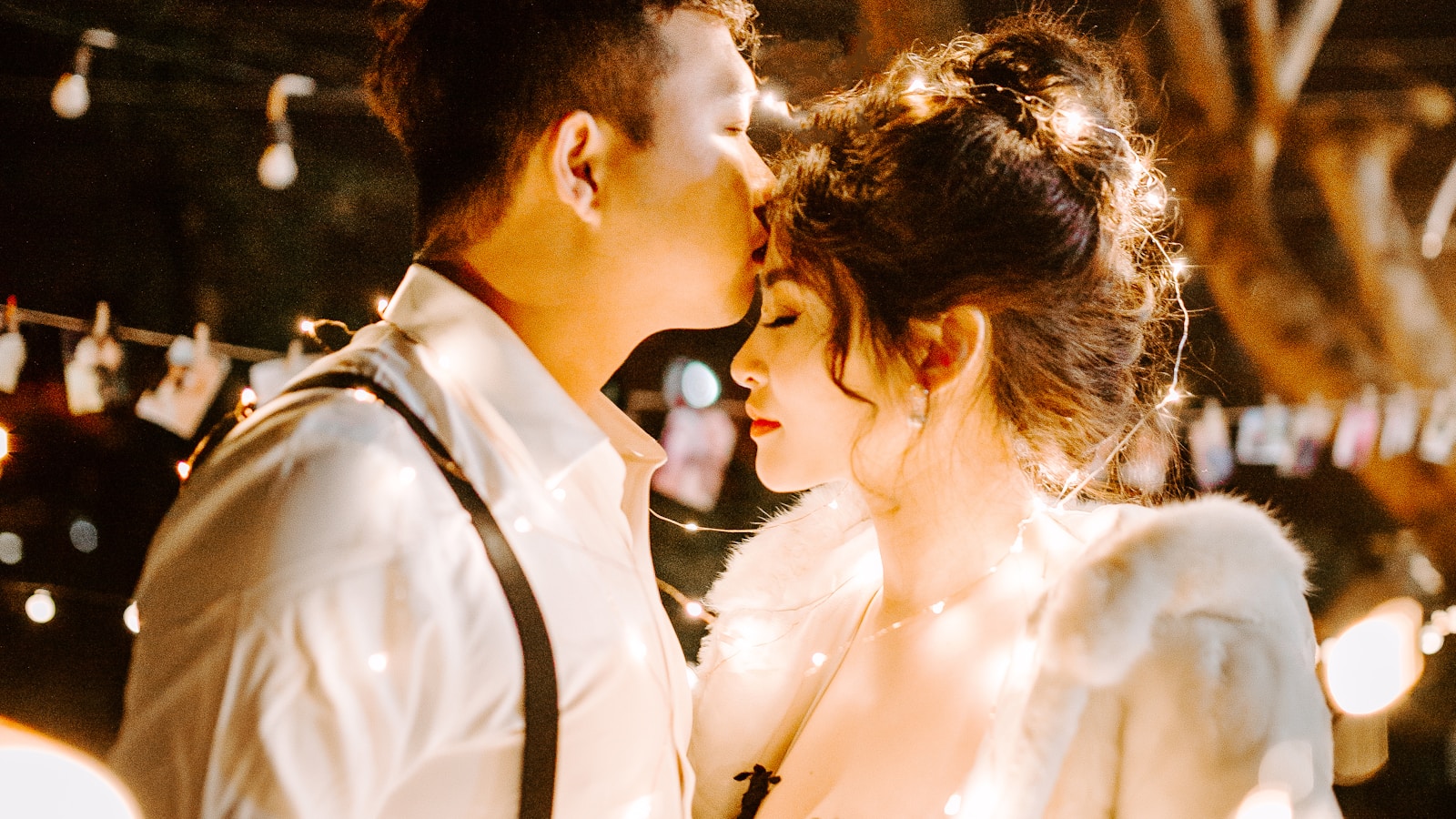 A young Asian couple leaning close, foreheads touching under warm evening light, the small kind of intimacy that comes back first after a baby.
