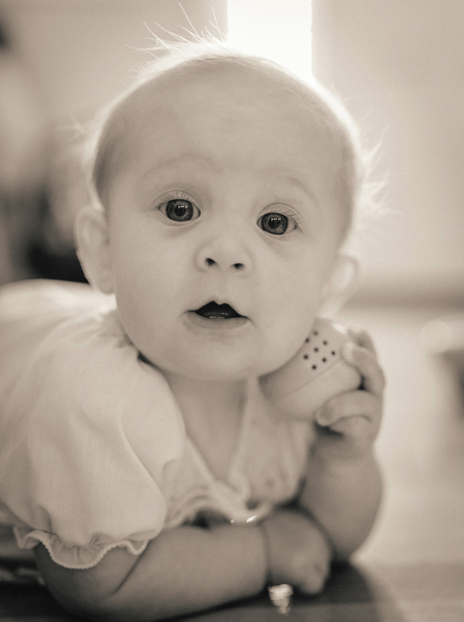 A baby lifting her head during tummy time, alert and looking forward, the quiet moment that means the neck muscles are doing the job