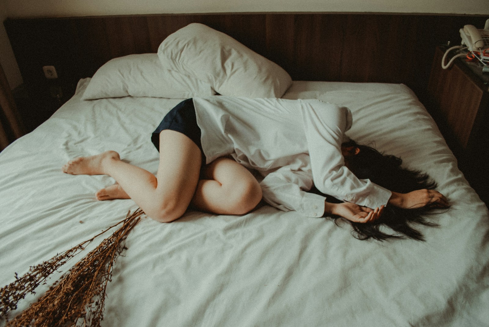 A new mother lying quietly on a bed under soft daylight, the kind of postpartum stillness when the body is busy bringing systems like the bladder back online