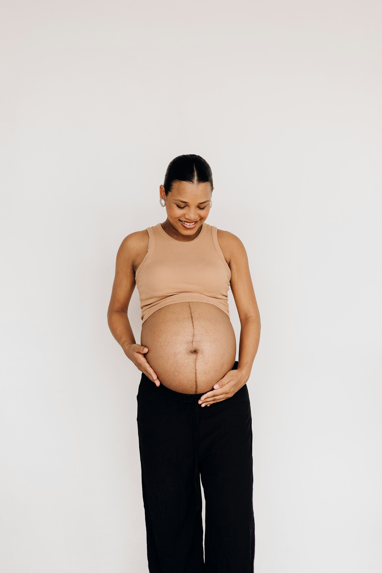 A third-trimester mum-to-be looking down at her bump, around the 32-week mark when reflux and heartburn usually peak